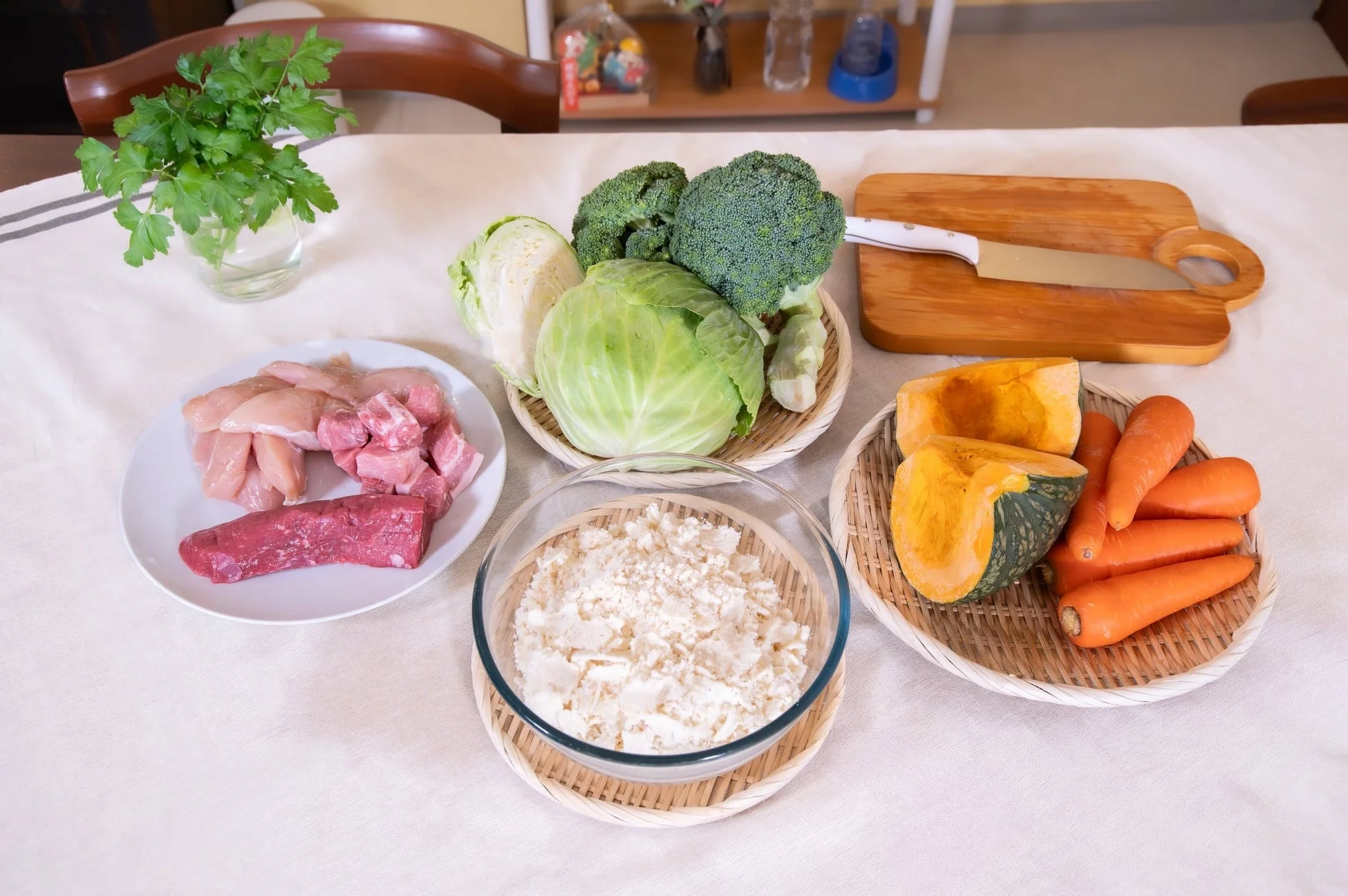 白いテーブルクロスの上に、新鮮な肉、野菜、そして米が並べられています。