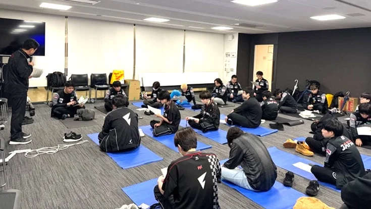 床に座って話を聞く若者のグループ