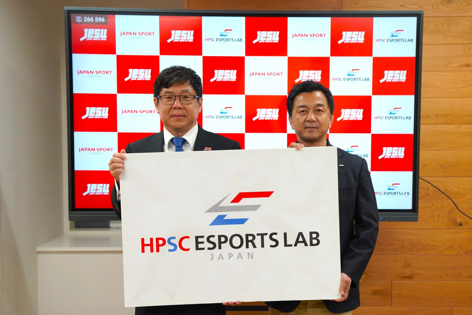 HPSC ESPORTS LAB JAPANのロゴボードを掲げる男性2人