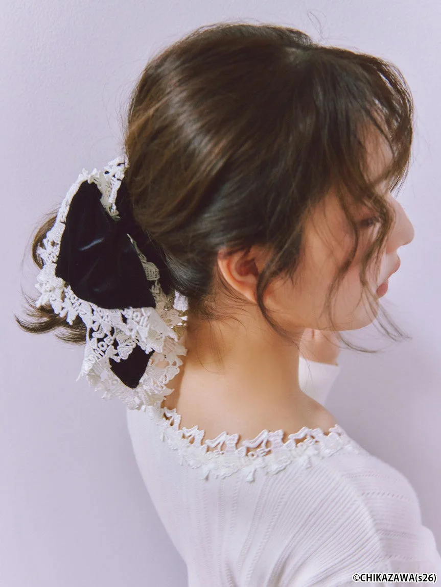 黒いベルベットのリボンと白いレースで飾られたヘアスタイルが特徴の女性の横顔です。