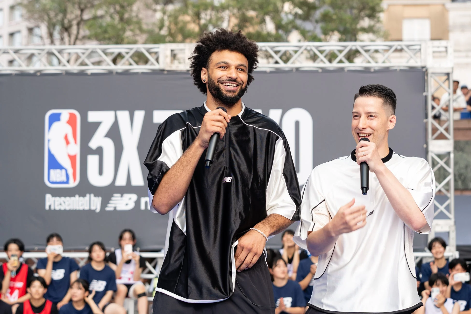 NBA 3Xイベントのステージで、2人の男性がマイクを手に笑顔で話しています。