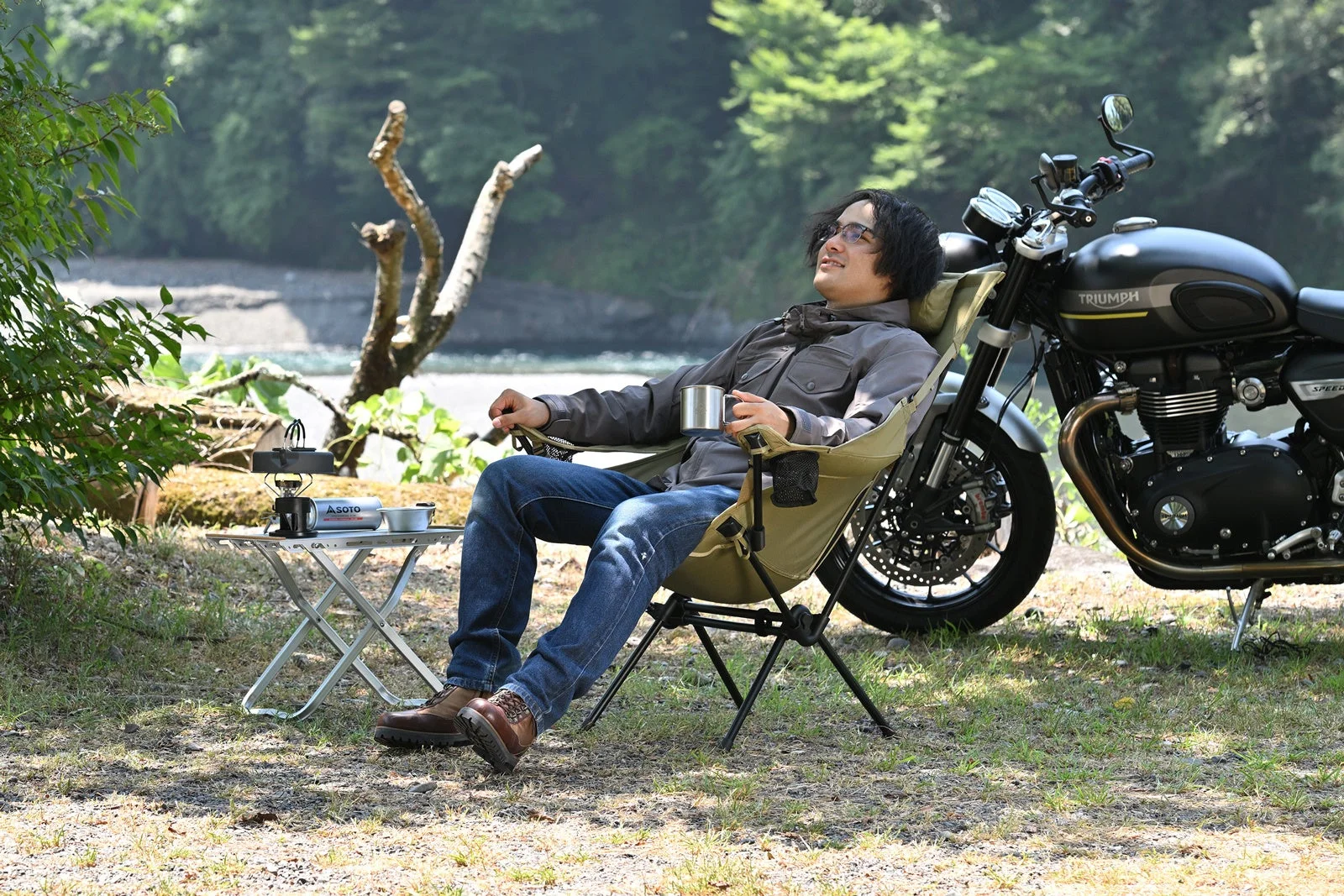 男性がバイクの横でキャンプチェアに座り、リラックスしている様子
