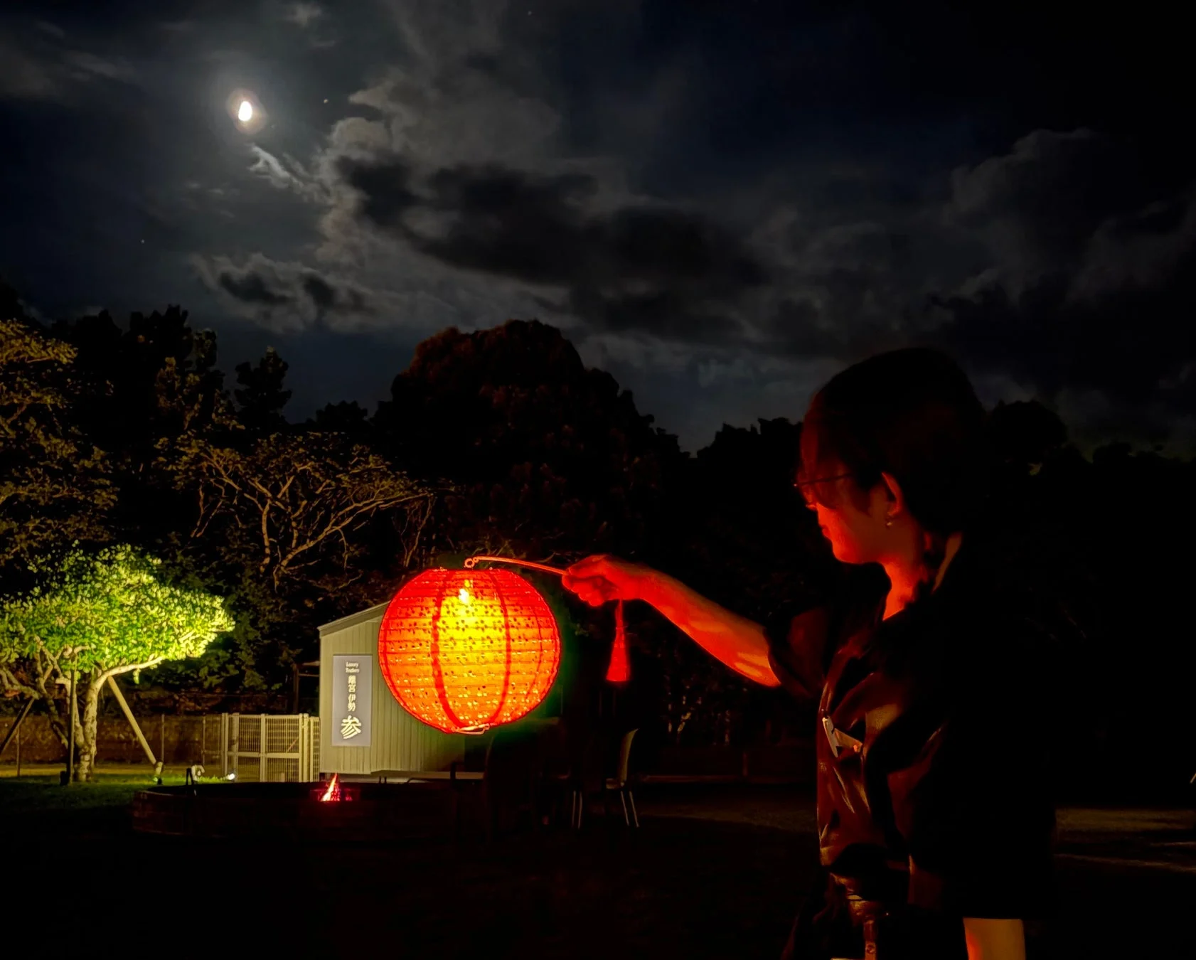 夜のキャンプで赤い提灯を持つ人物