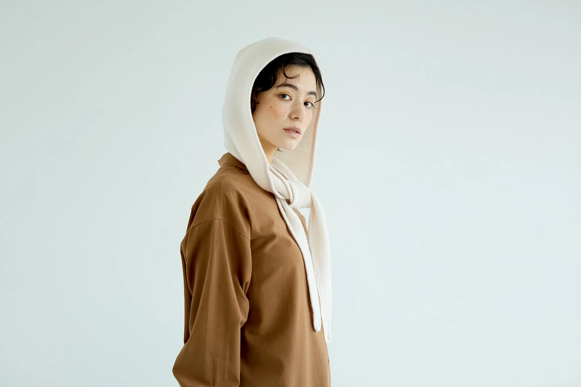 茶色のシャツとベージュのニットフードを着用した女性のポートレート