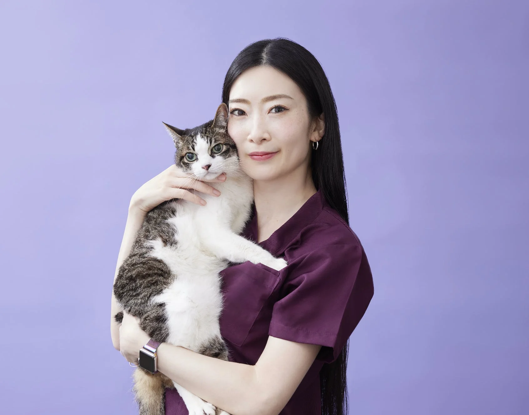 笑顔の女性が猫を優しく抱きかかえています