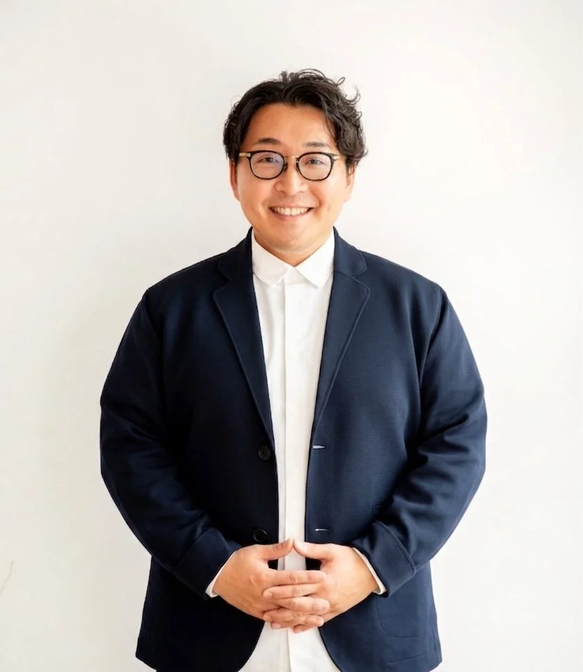 笑顔で両手を組む眼鏡をかけた男性