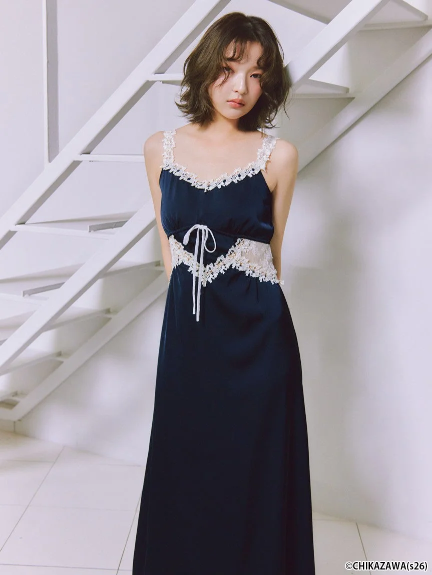 ネイビーのロングスリップドレスを着用したショートヘアの女性が立つポートレート。ドレスには白いレースがあしらわれ、落ち着いた表情を見せている。