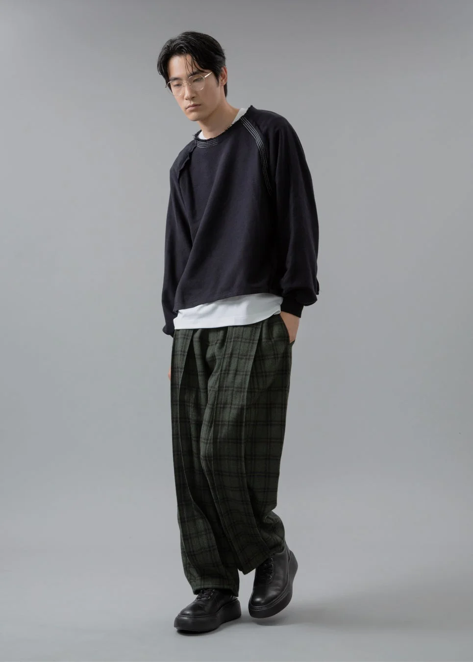 男性、黒いスウェット、緑のチェック柄ワイドパンツ