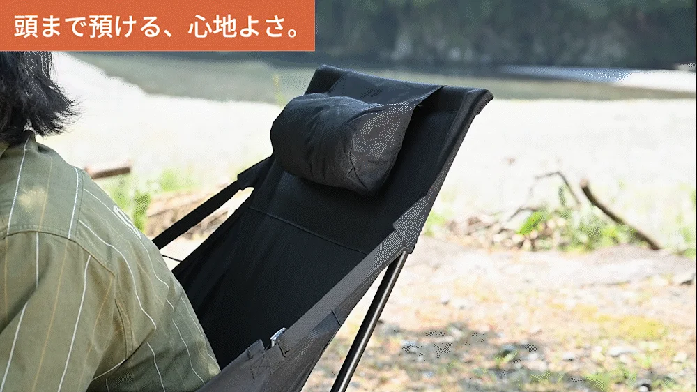 屋外で、頭までしっかり支えるヘッドレスト付きのキャンプチェアに座り、くつろぐ人物の画像