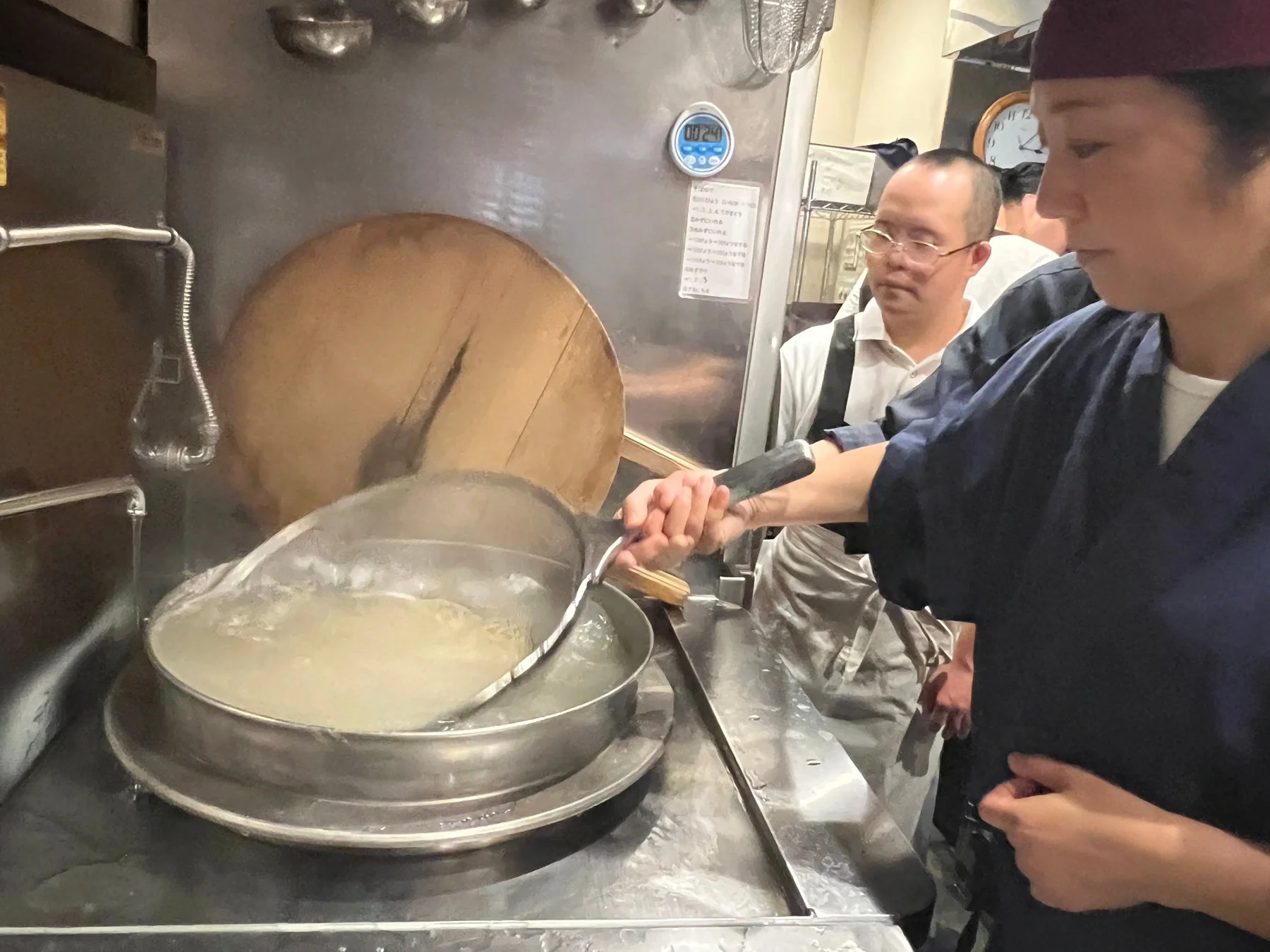 厨房で麺を茹でる調理師