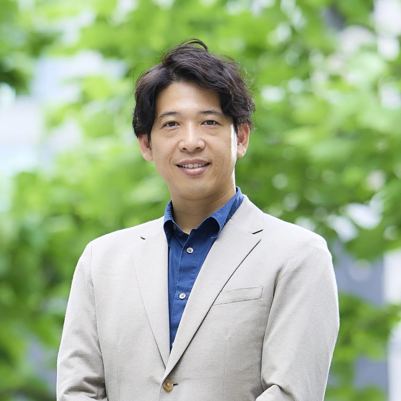 緑豊かな屋外を背景に笑顔の横澤淳平社長
