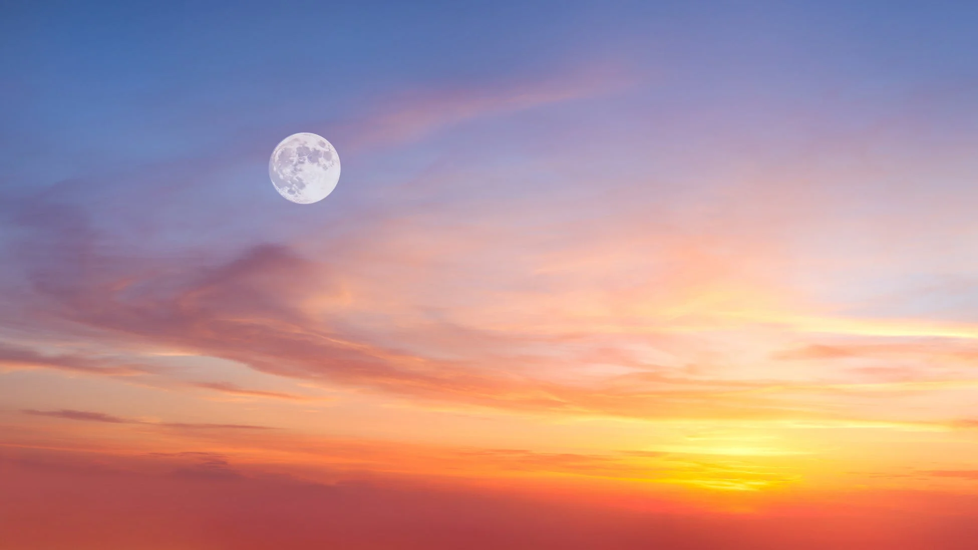 鮮やかな夕焼け空（または朝焼け空）に、大きく輝く満月が浮かんでいます。青、紫、ピンク、オレンジ、黄色へと移り変わる美しいグラデーションが印象的な幻想的な風景です。