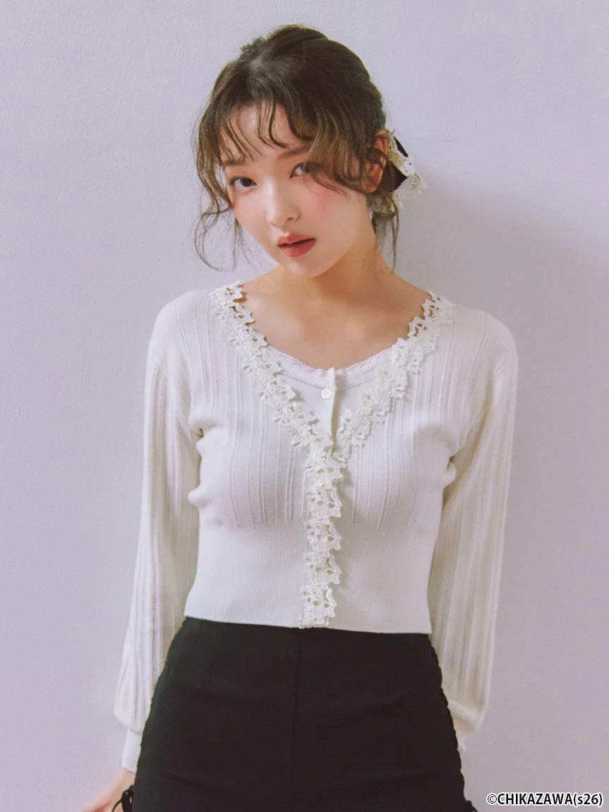 白いレース装飾のカーディガンと黒いスカートを着用した若い女性のポートレート。