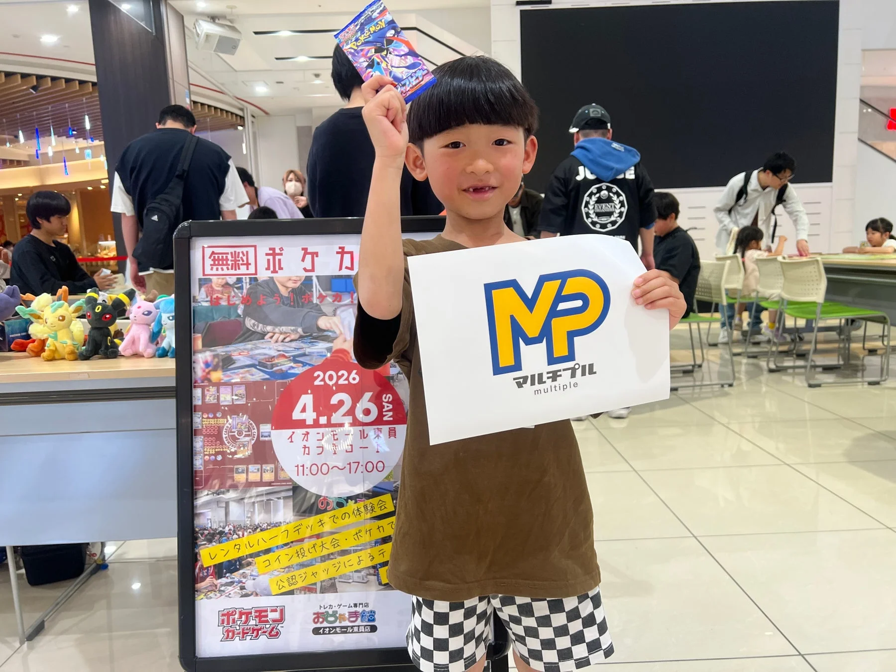 男の子がポケモンカードのパックと紙を持つ、イベントの様子