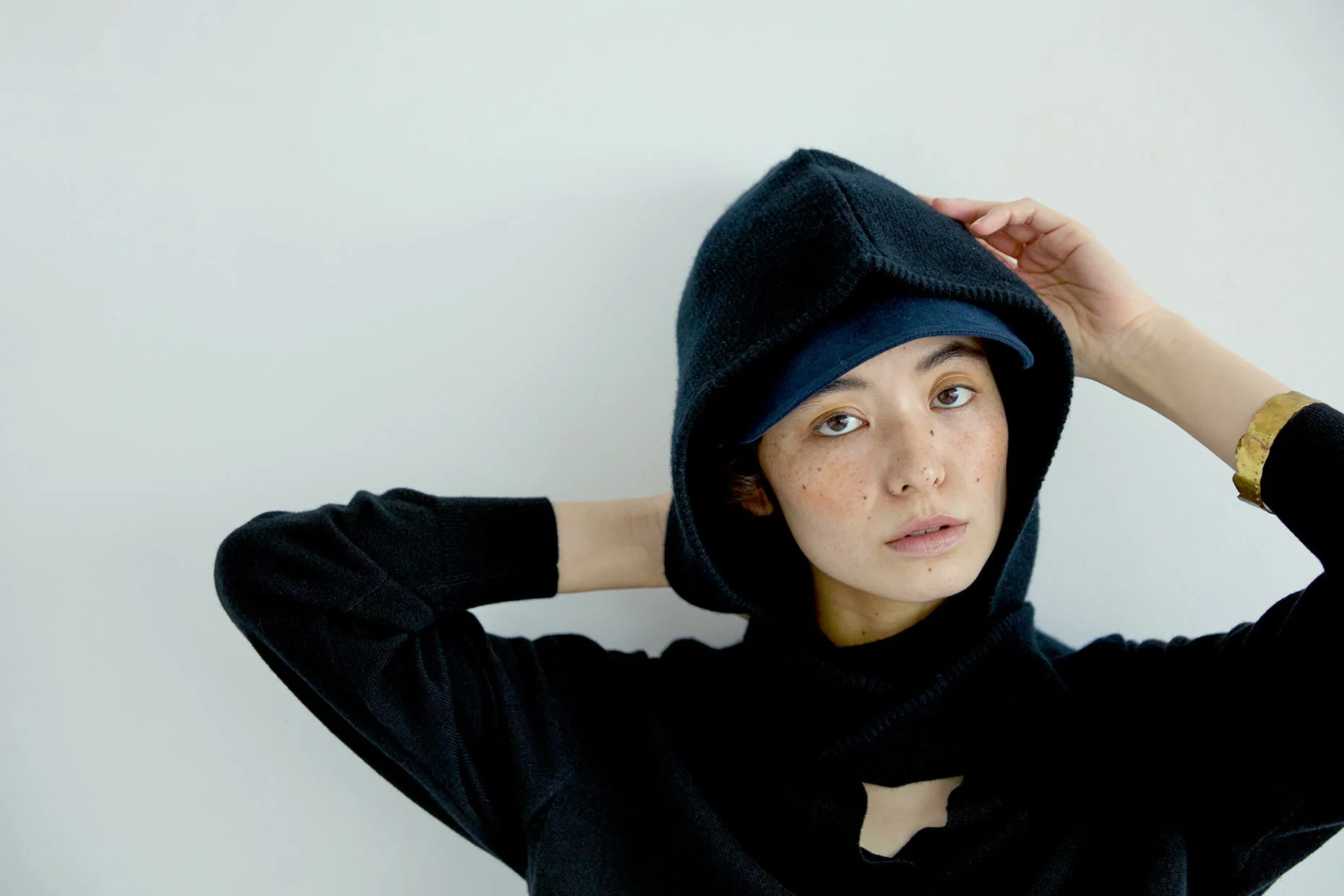 黒いフーディーとネイビーのキャップを着用した女性のポートレート