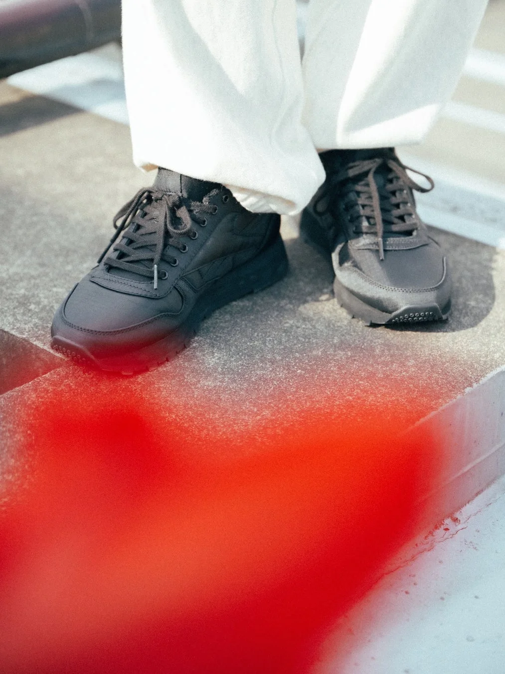白いパンツと黒いスニーカーの足元