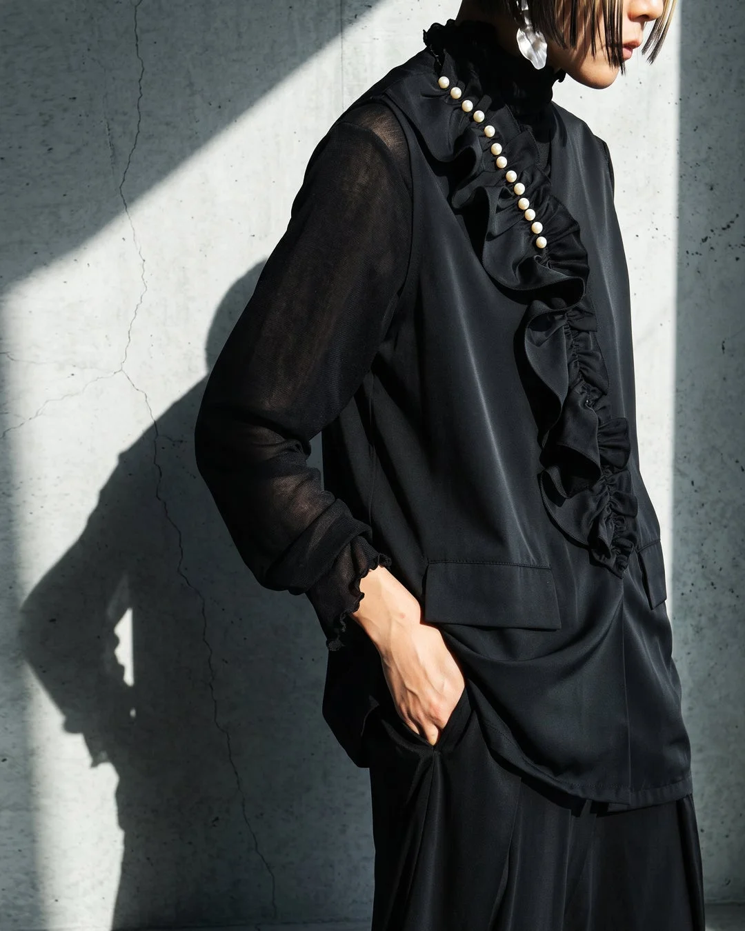 黒いラッフルブラウスとパールのファッション