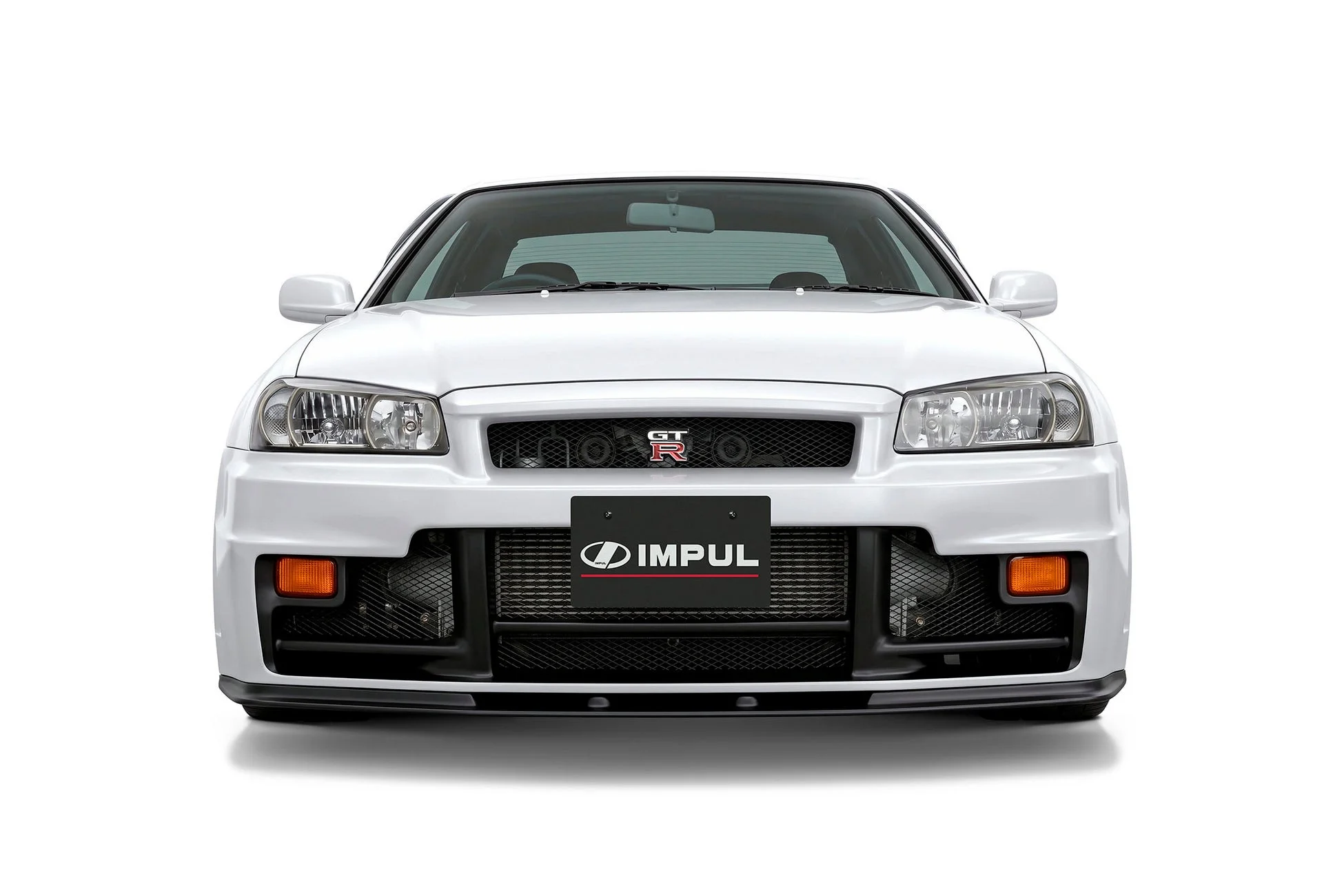 白いボディのスポーツカー、日産スカイラインGT-Rのフロント部分が写っています。IMPULのロゴが入ったカスタムパーツが特徴的で、力強い印象を与えます。